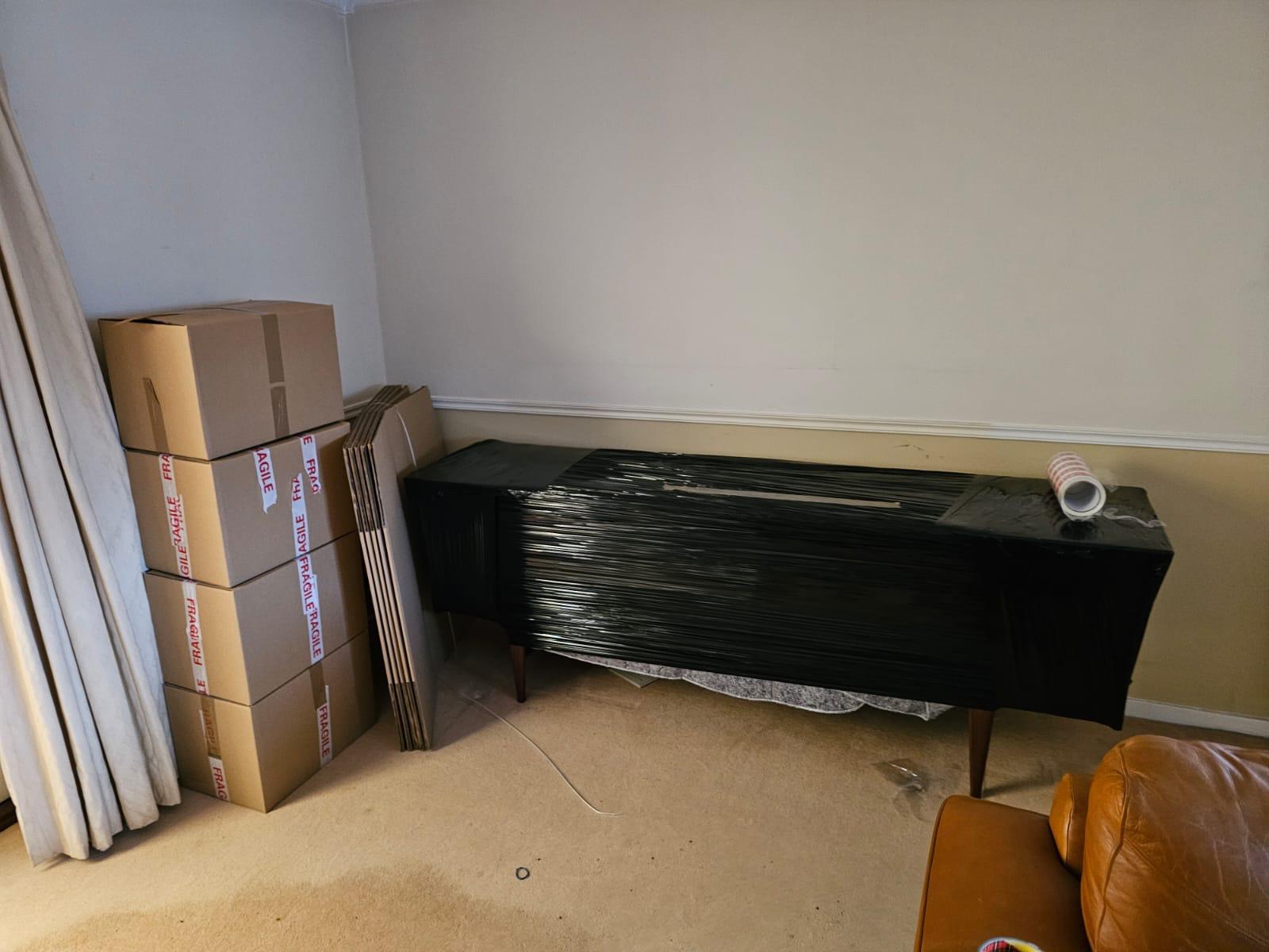 A wrapped console table and stacked cartons in a cleared living room