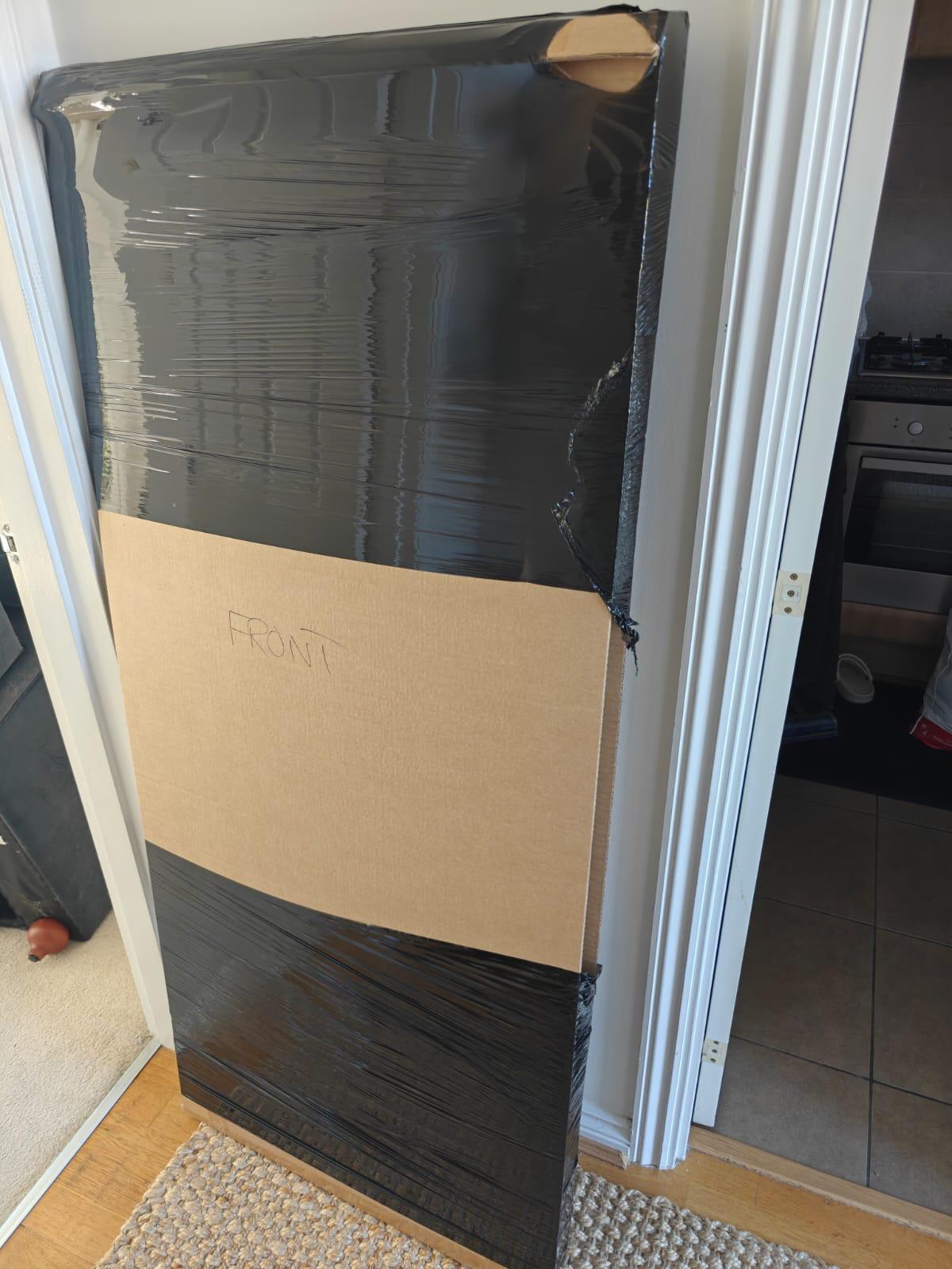 A tall cabinet wrapped and board-protected for the stairs